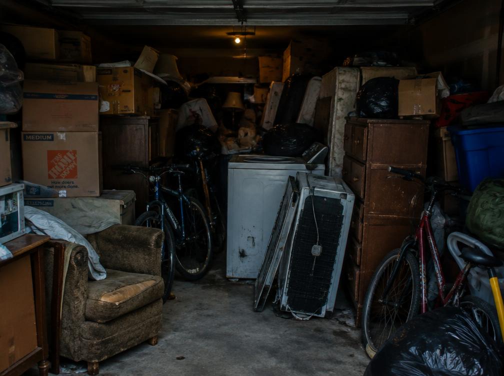 Garage packed wall to wall with boxes, furniture, and junk